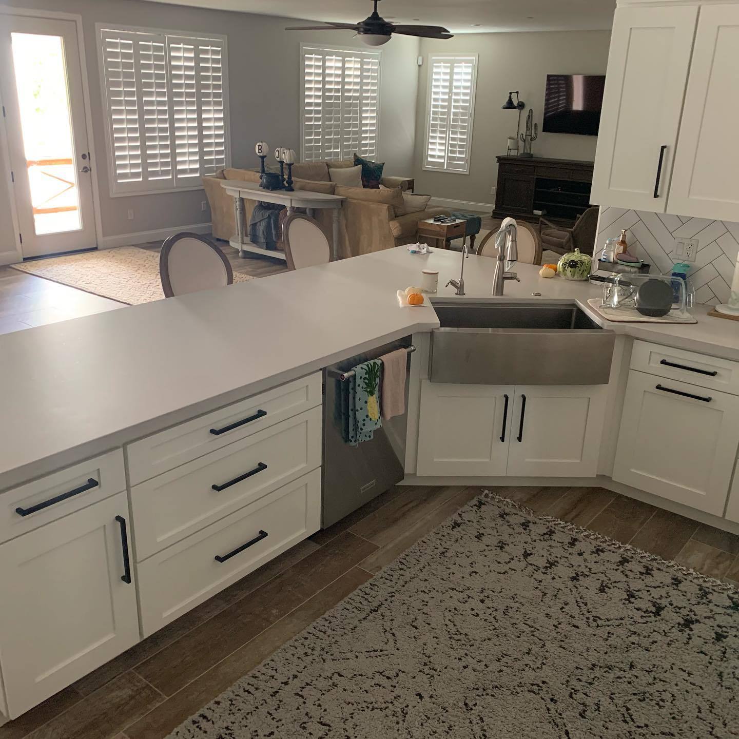 White quartz peninsula countertop with a stainless farmhouse sink