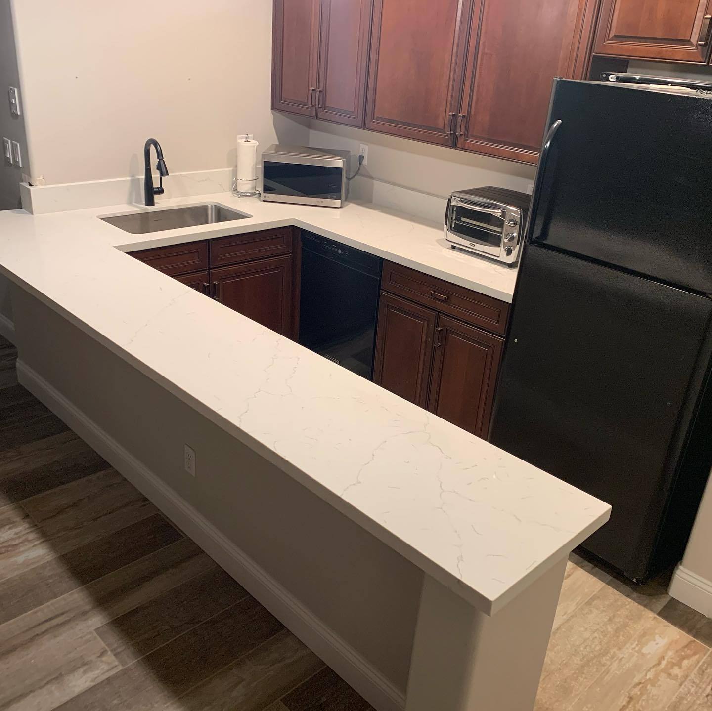 White quartz bar-height counter installed against cherry cabinetry