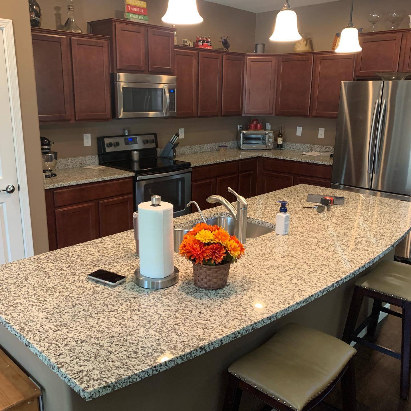 Speckled granite island countertop with cherry cabinetry behind it