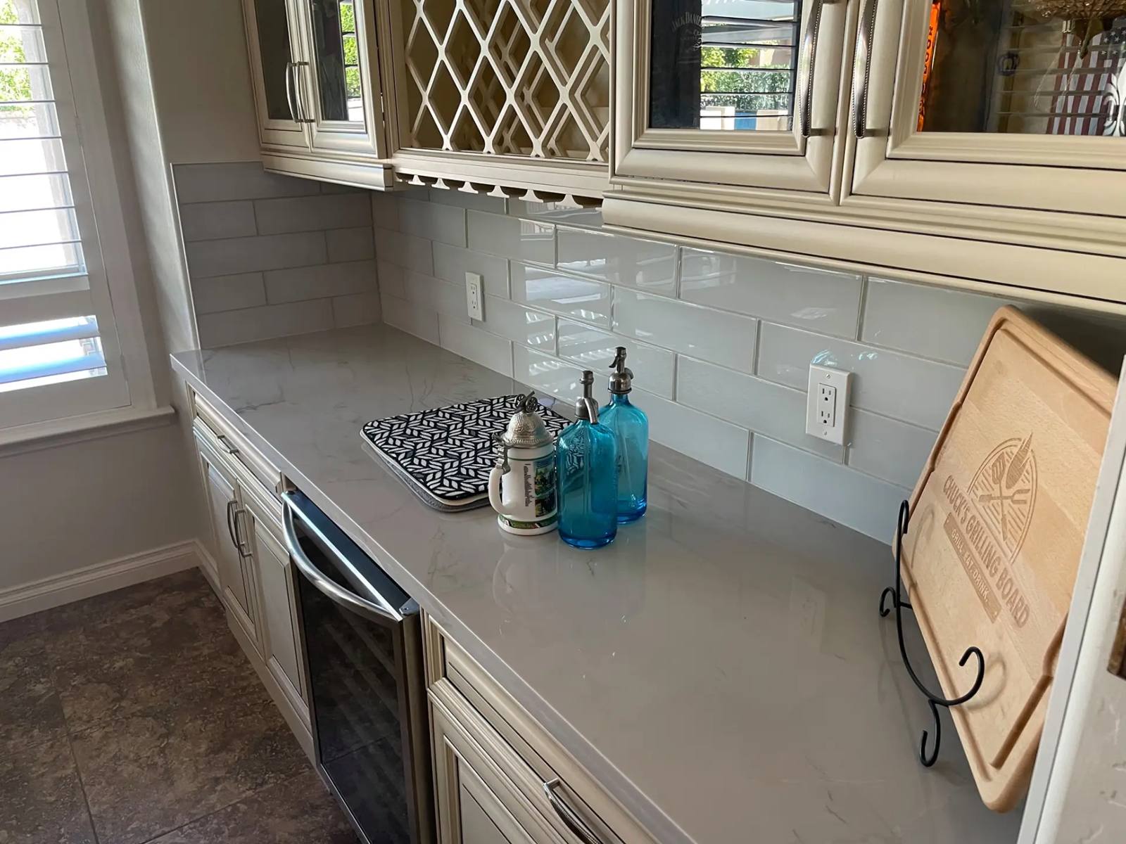 Marble-look quartz counter with a glass subway tile backsplash above it