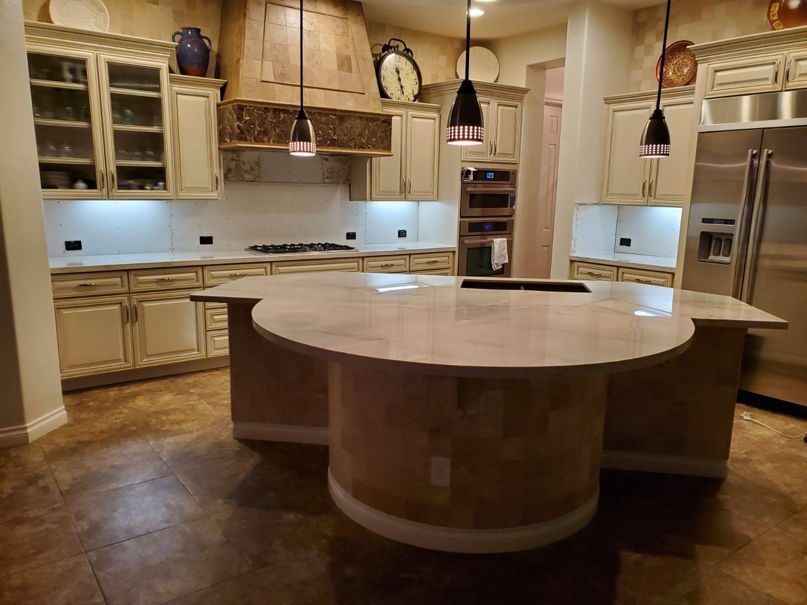 Curved marble-look island in a kitchen with travertine accents